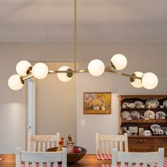 a dining room table with four chairs and a light fixture hanging from it's ceiling