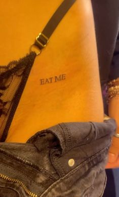 a woman's stomach with the words eat me tattooed on it