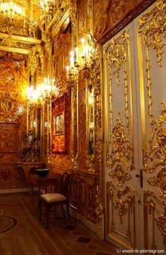 an ornately decorated room with gold paint and chandeliers on the walls, along with wooden flooring