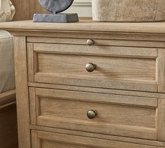 a close up of a wooden dresser with drawers and a clock on it's top