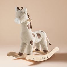 a stuffed giraffe sitting on top of a wooden rocking horse