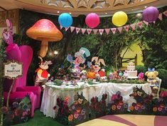 a table topped with lots of cake and decorations in front of a mushroom themed wall