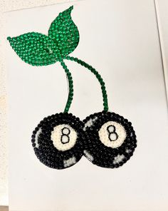 two black and white balls with green leaves on them, one has the letter b