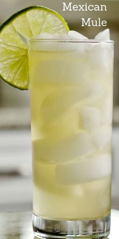 a tall glass filled with ice and lime