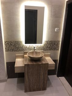 a bathroom with a sink, mirror and lights on the wall above it's counter