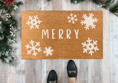 a door mat that says merry with snowflakes on it and two pairs of shoes next to it