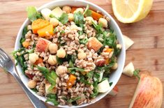 a white bowl filled with rice and vegetables next to an orange slice on a cutting board