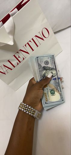 a person holding money in front of a valentine's day bag