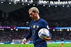 a man holding a soccer ball in front of a stadium full of people and lights