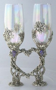 two silver goblets sitting next to each other on top of a white table