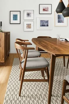 a dining room table with chairs and pictures on the wall