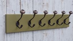 a row of hooks on a white wooden wall with five balls hanging from the hooks