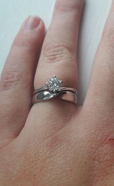 a woman's hand with a diamond ring on top of her left hand,