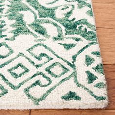 a green and white rug on the floor with wood floors in the background at home