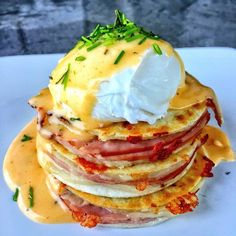 a stack of pancakes covered in cheese and ham