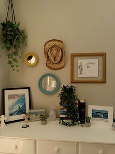 a white dresser topped with pictures and plants