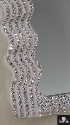 a mirror that has some kind of design on it's side and is covered in crystals