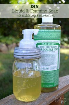 two bottles of liquid and soap sitting on top of a wooden bench with trees in the background