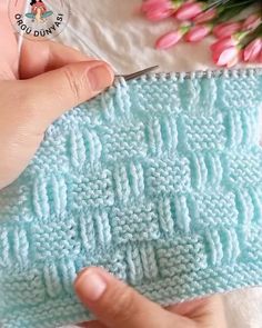 someone is crocheting the stitchs on a blue knitted piece of cloth