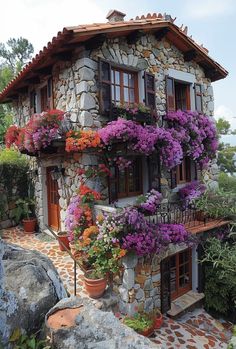 a stone house with flowers growing on the windows and balconies over the door