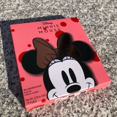 a minnie mouse pin sitting on top of a pink box