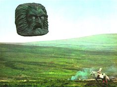 a man riding a horse next to a giant gorilla head on top of a hill