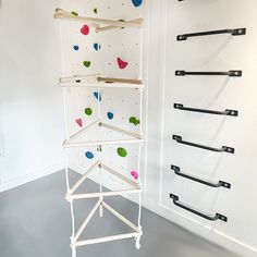 there is a climbing wall in the room with several pegs on it and some black handles