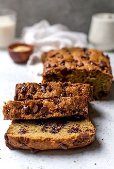 slices of chocolate chip banana bread on a white surface with two cups of milk in the background