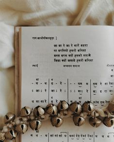 an open book sitting on top of a bed next to a bunch of bell bells