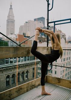 a woman doing yoga on top of a building