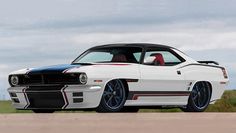 a white muscle car with red and black stripes parked on the side of a road