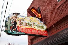 a mexican food restaurant sign hanging off the side of a building in front of a red brick building