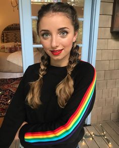 a woman with long hair wearing a rainbow sweater