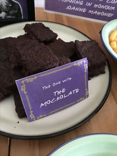 some brownies are sitting on a plate with a sign that says the one with the chocolate