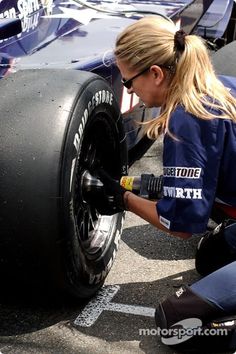 a woman is changing the tire on a race car