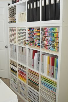 a white bookcase filled with lots of books next to a wall full of folders