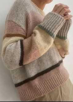 a woman is wearing a sweater with multicolored stripes