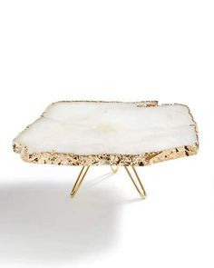 a white tray sitting on top of a metal stand with two legs and a large piece of rock in the middle