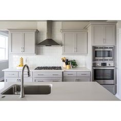 a kitchen with stainless steel appliances and white counter tops, along with an island in the middle