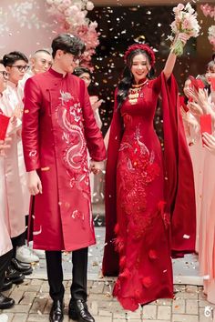 a man and woman dressed in red are walking through confetti