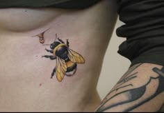 a woman's stomach with a bee tattoo on it