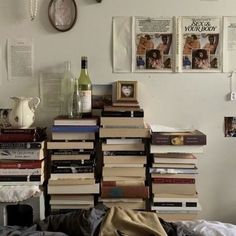 a stack of books sitting on top of a bed next to a bottle of wine