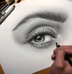 someone drawing an eye with pencils on paper