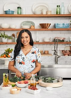 a woman standing in front of a counter with food on it and bowls around her