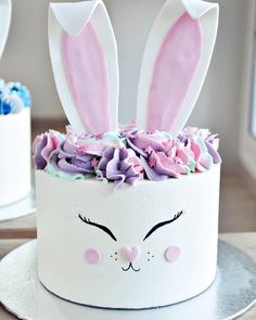 a white cake with pink and purple frosting decorated like a bunny's face