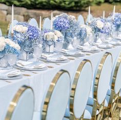 a long table is set with blue and white centerpieces, silverware, and candles