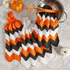 an orange and black crochet dishcloth next to a pot holder with a whisk on it