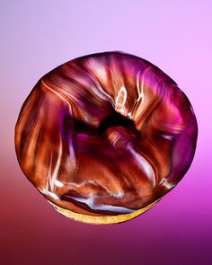 a donut that is in the air on a purple and pink background with light reflections