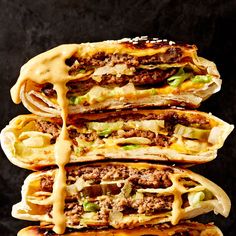 four cheeseburger sandwiches stacked on top of each other with sauce drizzled over them