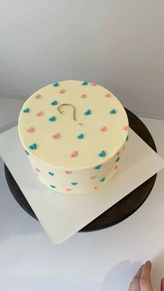 a white cake with pink, blue and green sprinkles sitting on top of a black plate